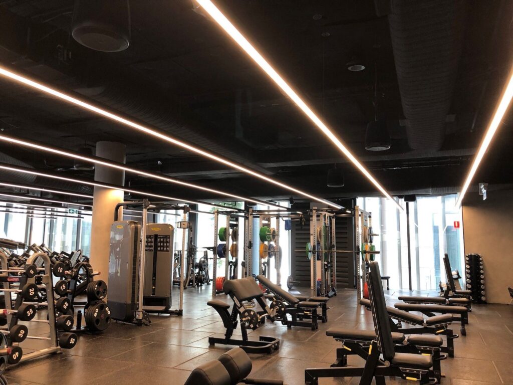 Imagem da área de treino da academia, sendo visivel o projeto de sonorização e as caixas de som instaladas.